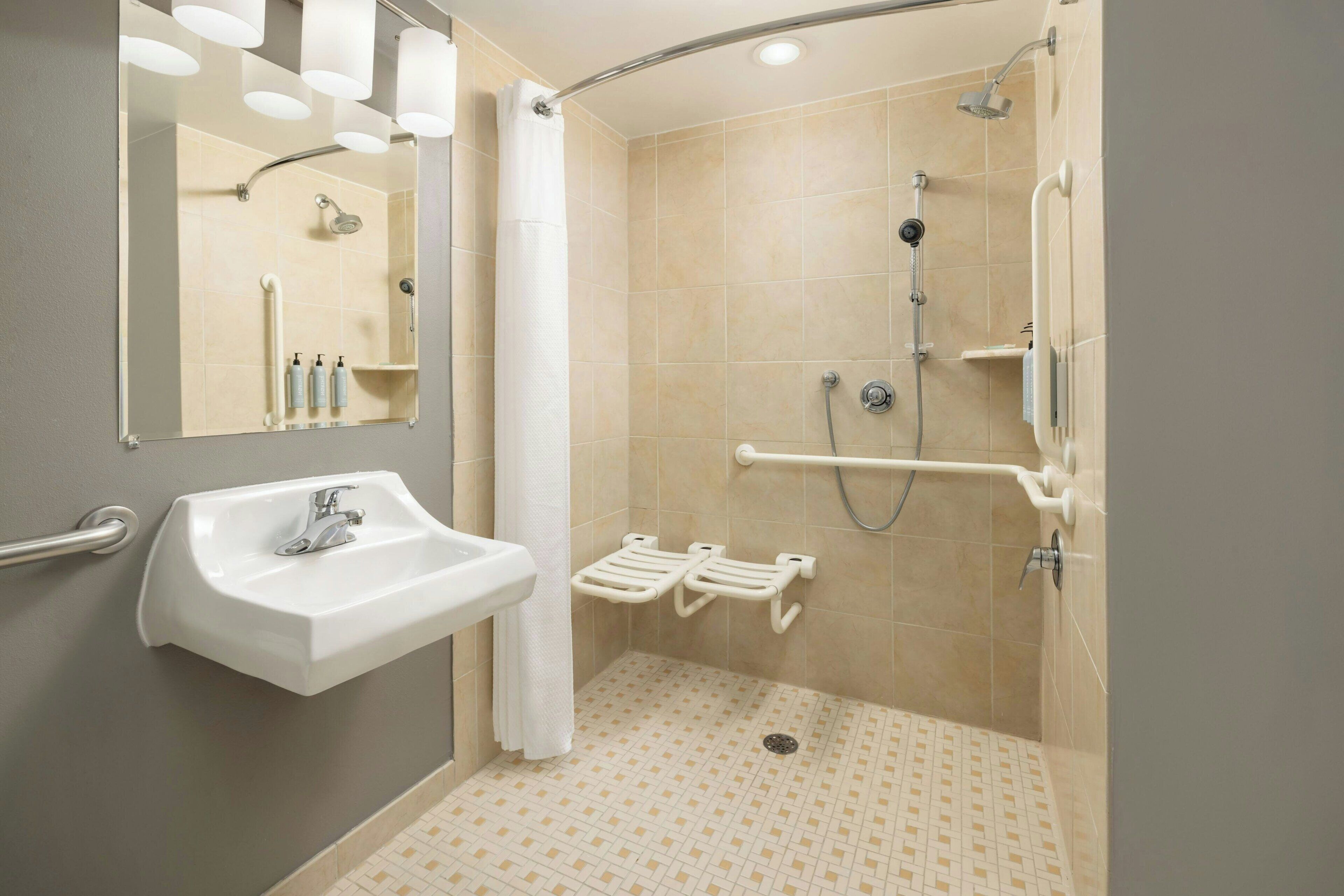 Un baño con ducha, lavabo, espejo y barandilla.