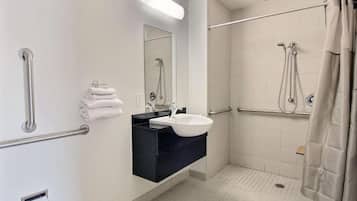 A bathroom with a white sink, a mirror, a towel rack, and a shower area.
