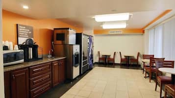 A hotel kitchen with a microwave, coffee maker, refrigerator, and a sign about morning charge.