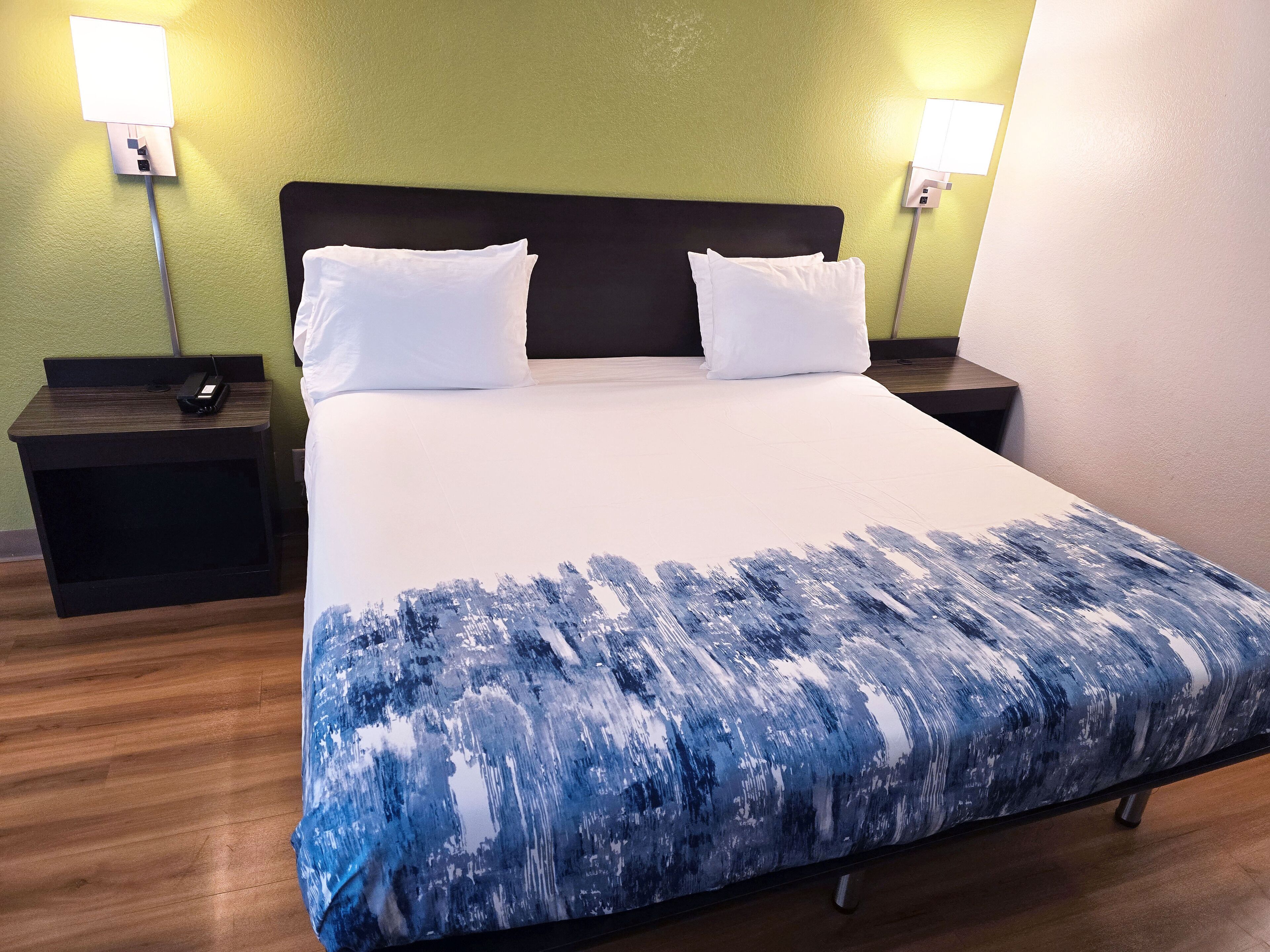 Una habitación de hotel con una cama grande, dos mesitas de noche y dos lámparas de pared.