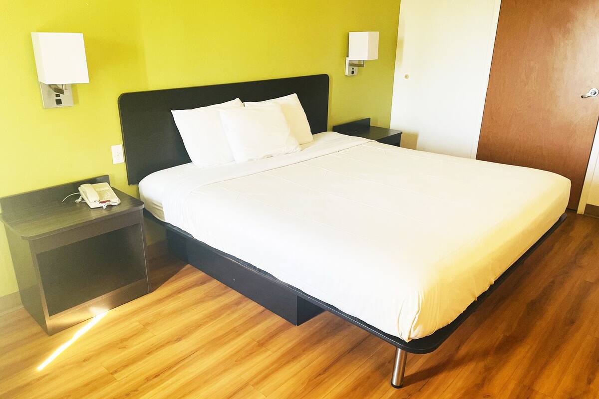 Ein Hotelzimmer mit einem Bett, Holzboden und zwei Nachttischen mit Lampen.