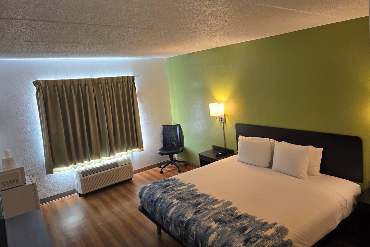 Ein Hotelzimmer mit Bett, Schreibtisch, Stuhl, Lampe und Heizung.