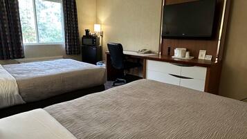 Ett hotellrum med två sängar, ett skrivbord med en dator, en tv och en kaffebryggare.