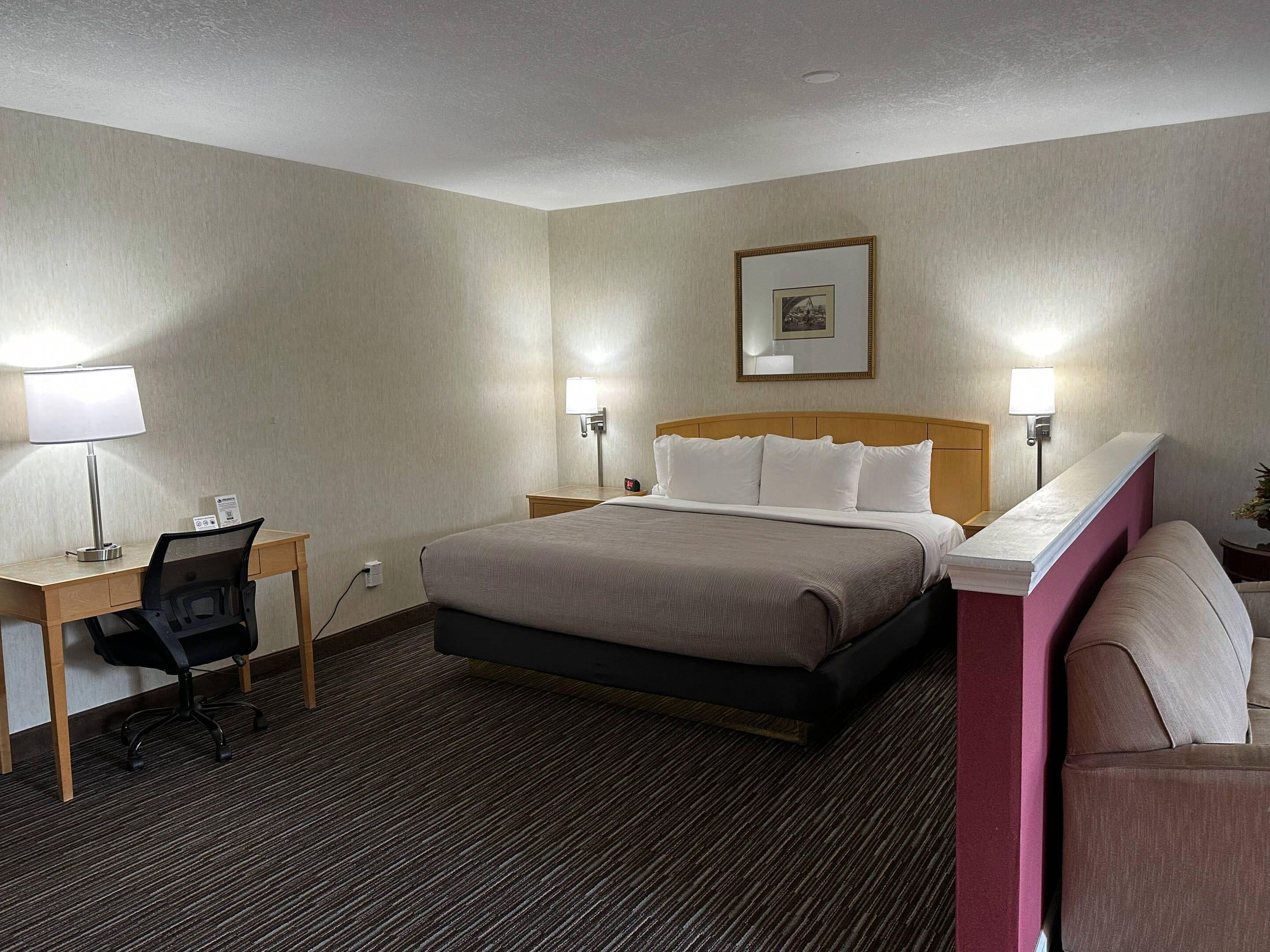 Ein Hotelzimmer mit Bett, Schreibtisch, Stuhl und zwei Nachttischlampen.