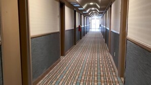 A long, narrow hotel corridor with a patterned floor, doors on both sides, and a fire extinguisher mounted on the wall. - Quality Inn near Toms River Corporate Park (Manchester Township)