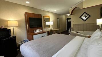 Camera d'albergo con un ampio letto, una scrivania con televisore a schermo piatto, una lampada da scrivania, uno specchio, un telefono, un cestino e una vasca da bagno.
