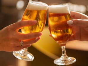 Dos manos sosteniendo vasos de cerveza, probablemente en un ambiente social.
