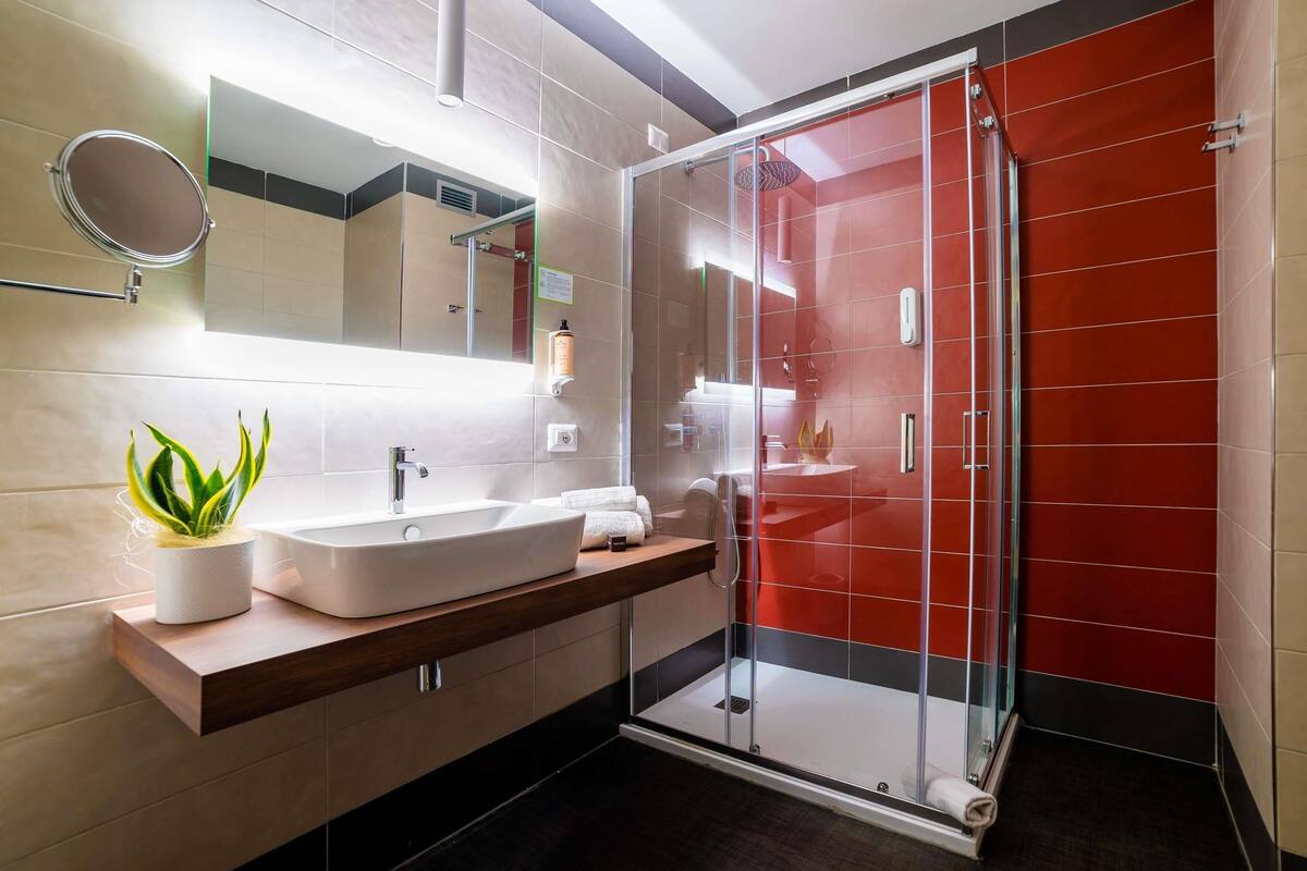 A modern bathroom with a large sink, mirror, and a glass shower enclosure.