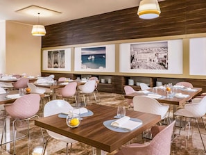 A restaurant with multiple tables, each set with white plates, cutlery, and glasses.