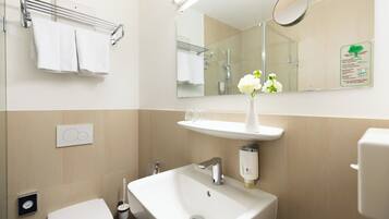 A modern bathroom with a white sink, a mirror, and a towel rack.
