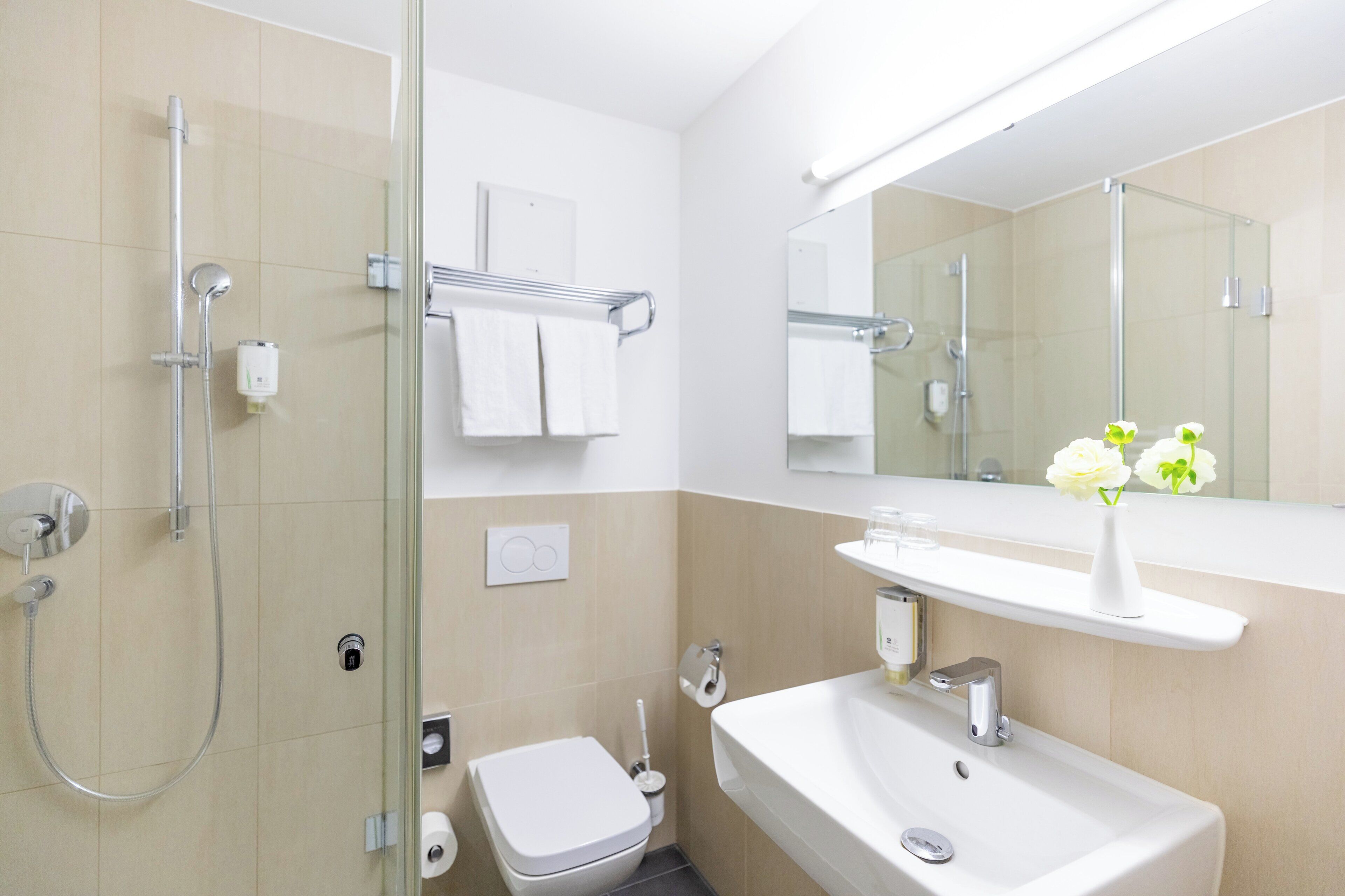 Un baño moderno con cabina de ducha de vidrio, un lavabo blanco y un espejo sobre él.