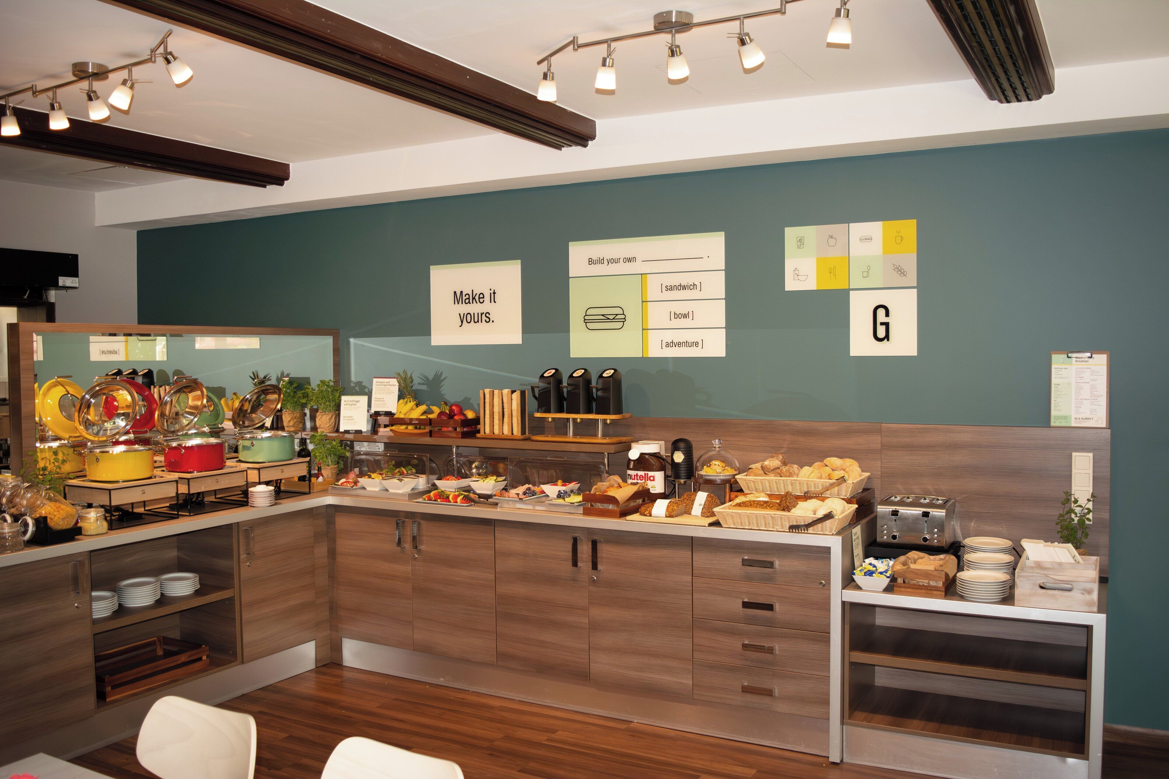 Zona de desayuno tipo bufé con diversas opciones de comida y una pared con mensajes inspiradores.