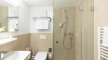 Un baño moderno con ducha de vidrio, lavamanos blanco y un inodoro.