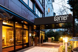 A hotel entrance with a sign reading 'Garnier An IHG Hotel.'