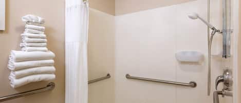 A bathroom with a shower, grab bars, a towel rack, and a soap dish.