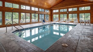 An indoor swimming pool with wooden walls and large windows.