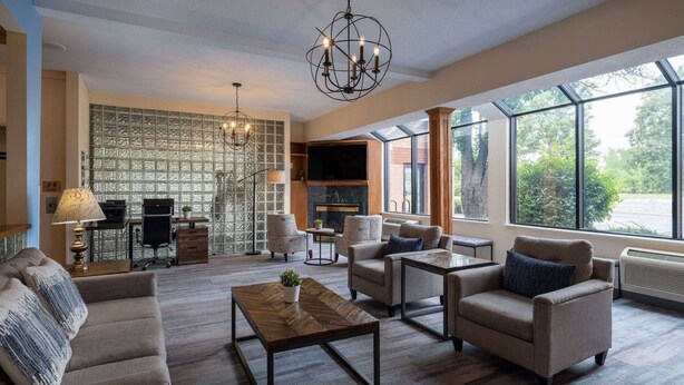 A spacious living room with a fireplace, comfortable seating, a coffee table, and large windows offering a view of the outdoors.