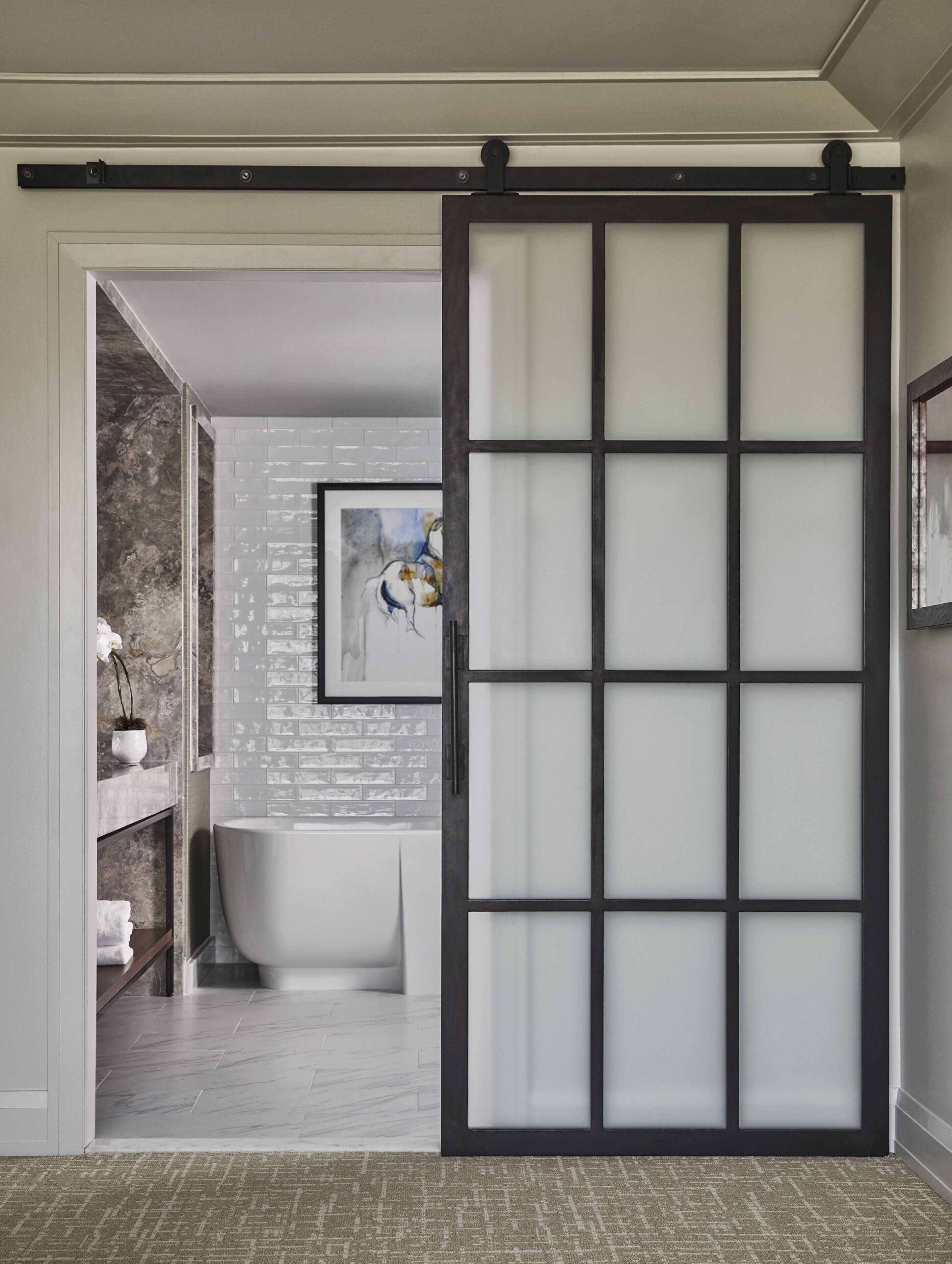 Une salle de bain comprenant une baignoire, des toilettes et un lavabo. Elle est dotée d’une porte coulissante avec des panneaux en verre dépoli.