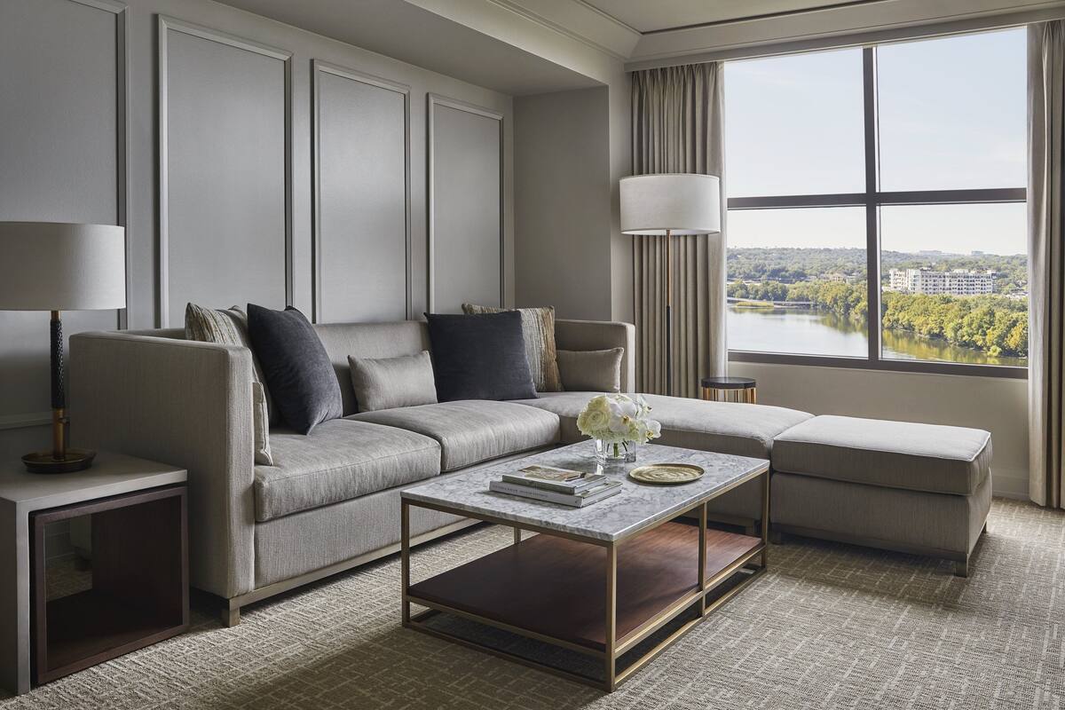 Ein modernes Wohnzimmer mit einer Eckcouch, einem Couchtisch und Seeblick durch große Fenster.
