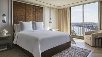 Camera d'albergo moderna con un letto grande, vista sul fiume e un balcone con ringhiera.