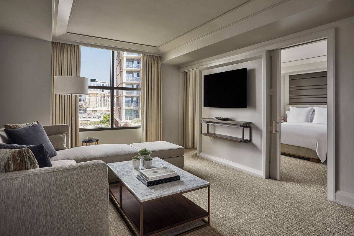 Ein modernes Hotelzimmer mit einer Couch, einem Couchtisch, einem Fernseher und einem Bett.