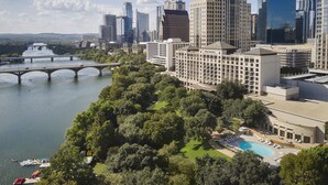 A hotel with a swimming pool, surrounded by lush greenery and a river. - Four Seasons Hotel Austin (Austin)