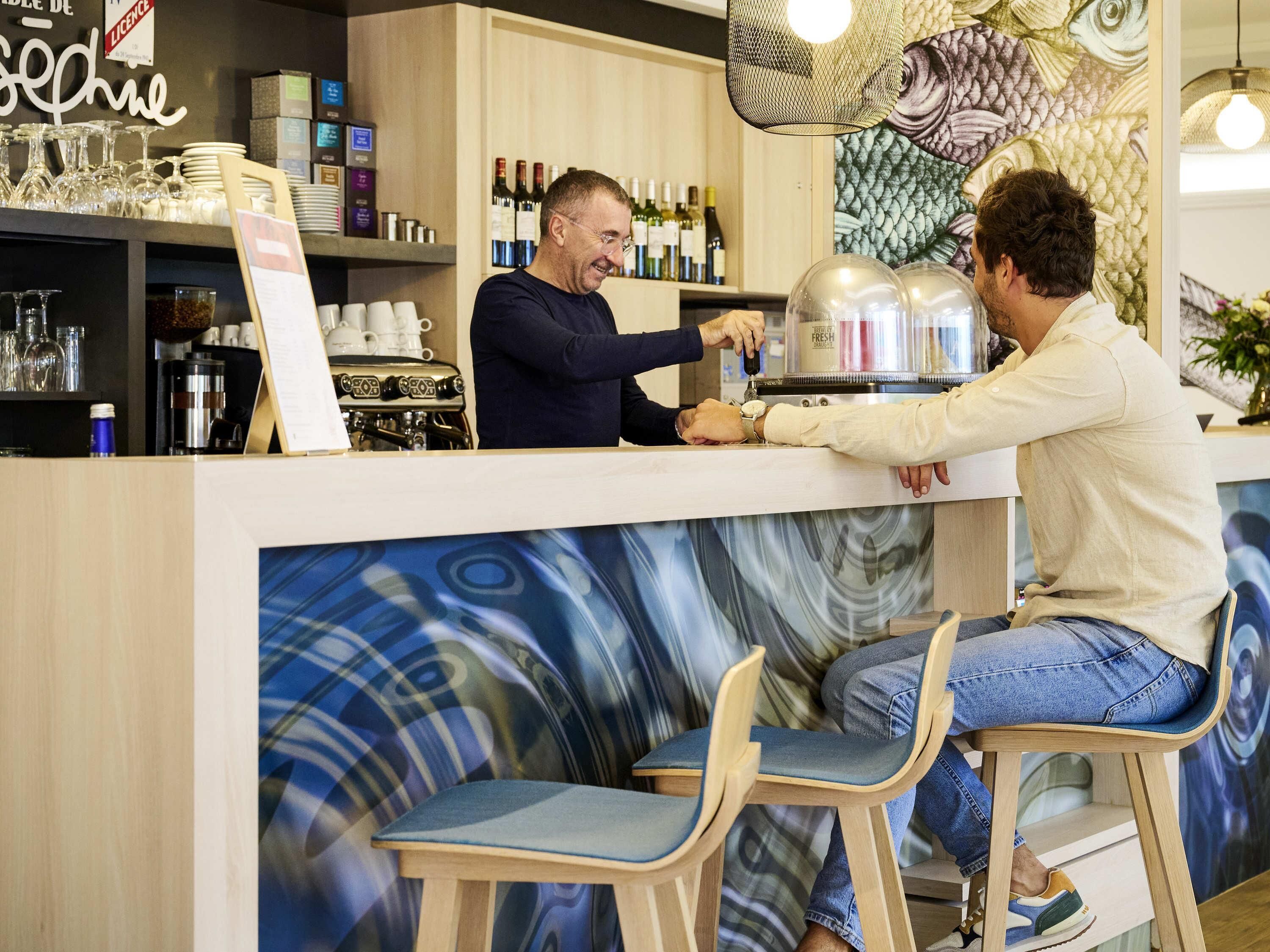 A bar area with a counter, bar stools, and a wall with a fish mural.