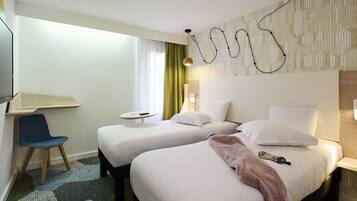 Une chambre d’hôtel avec deux lits, un bureau, une chaise et un mur décoré de motifs.