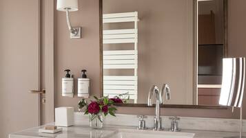A bathroom with a marble sink, two faucets, a mirror, a towel rack, and two bottles of hand soap.