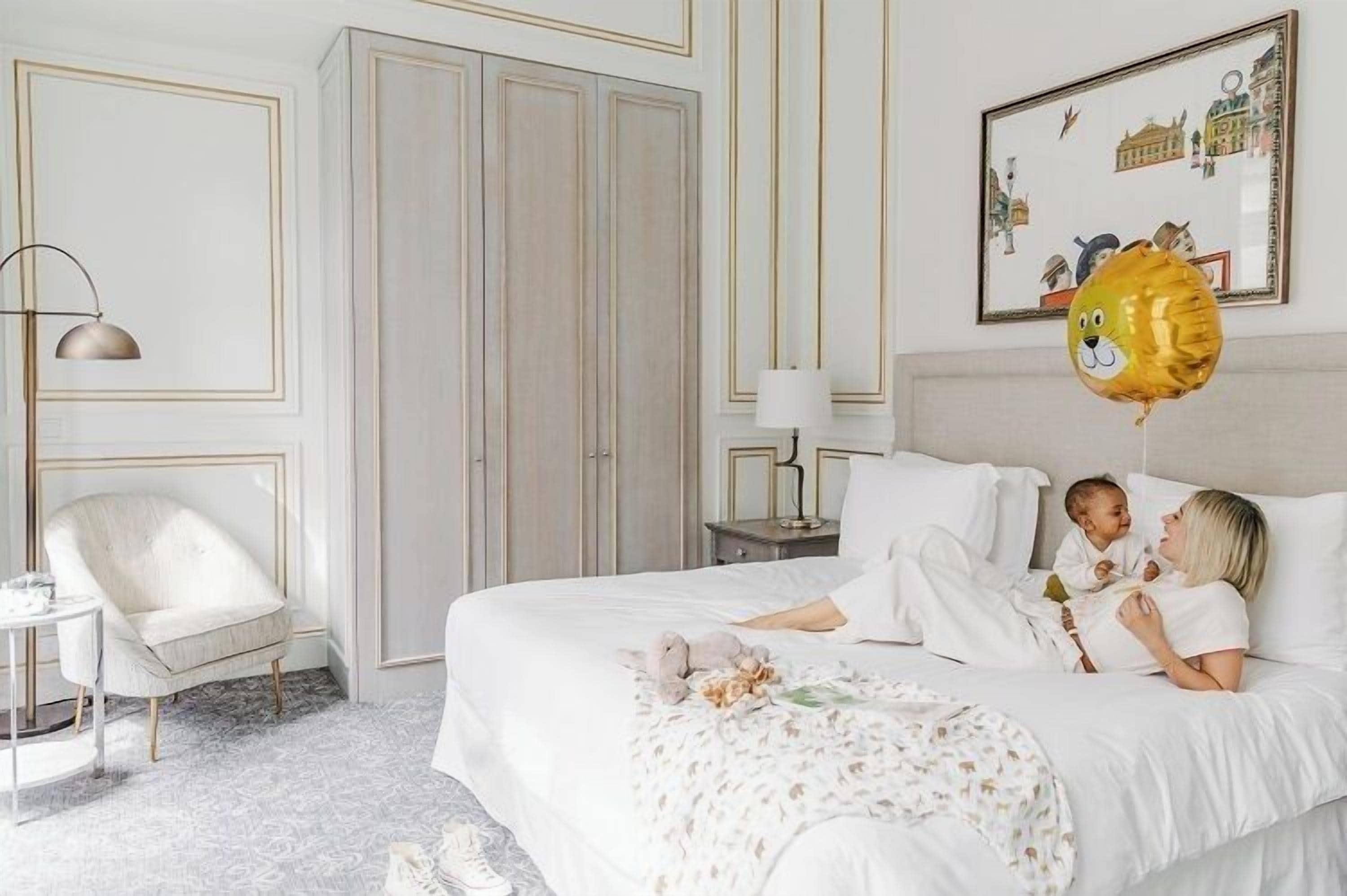 A bedroom with a bed, a chair, a nightstand, and a wall-mounted lamp.