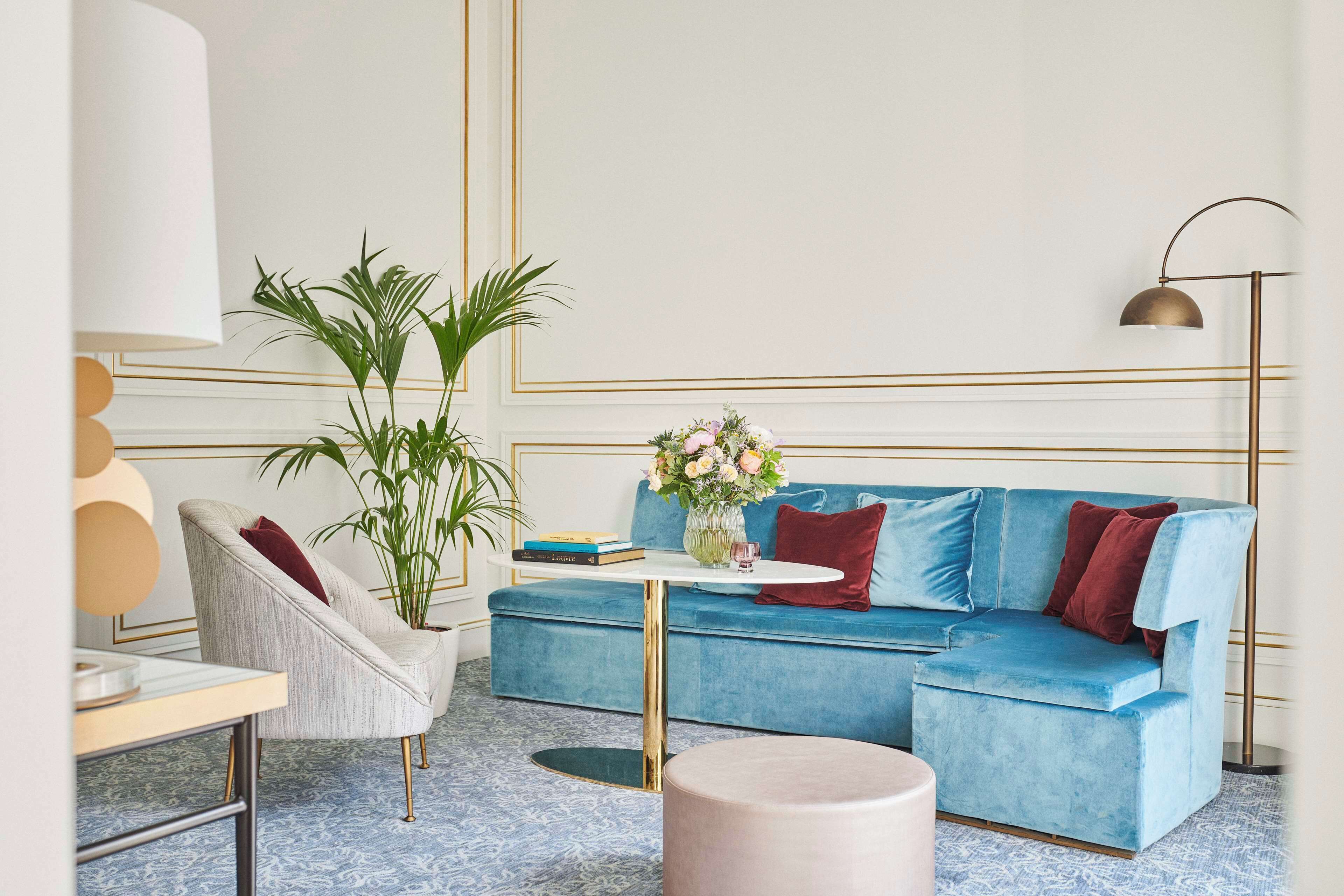 A modern living room with a blue sofa, a round coffee table, a white lamp, and a potted plant.