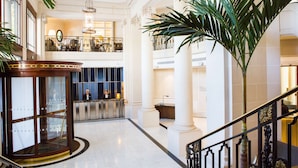 A lobby with a revolving door, a reception desk, and a staircase with ornate railings.
