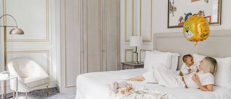 A bedroom with a bed, a chair, a nightstand, and a framed picture on the wall.