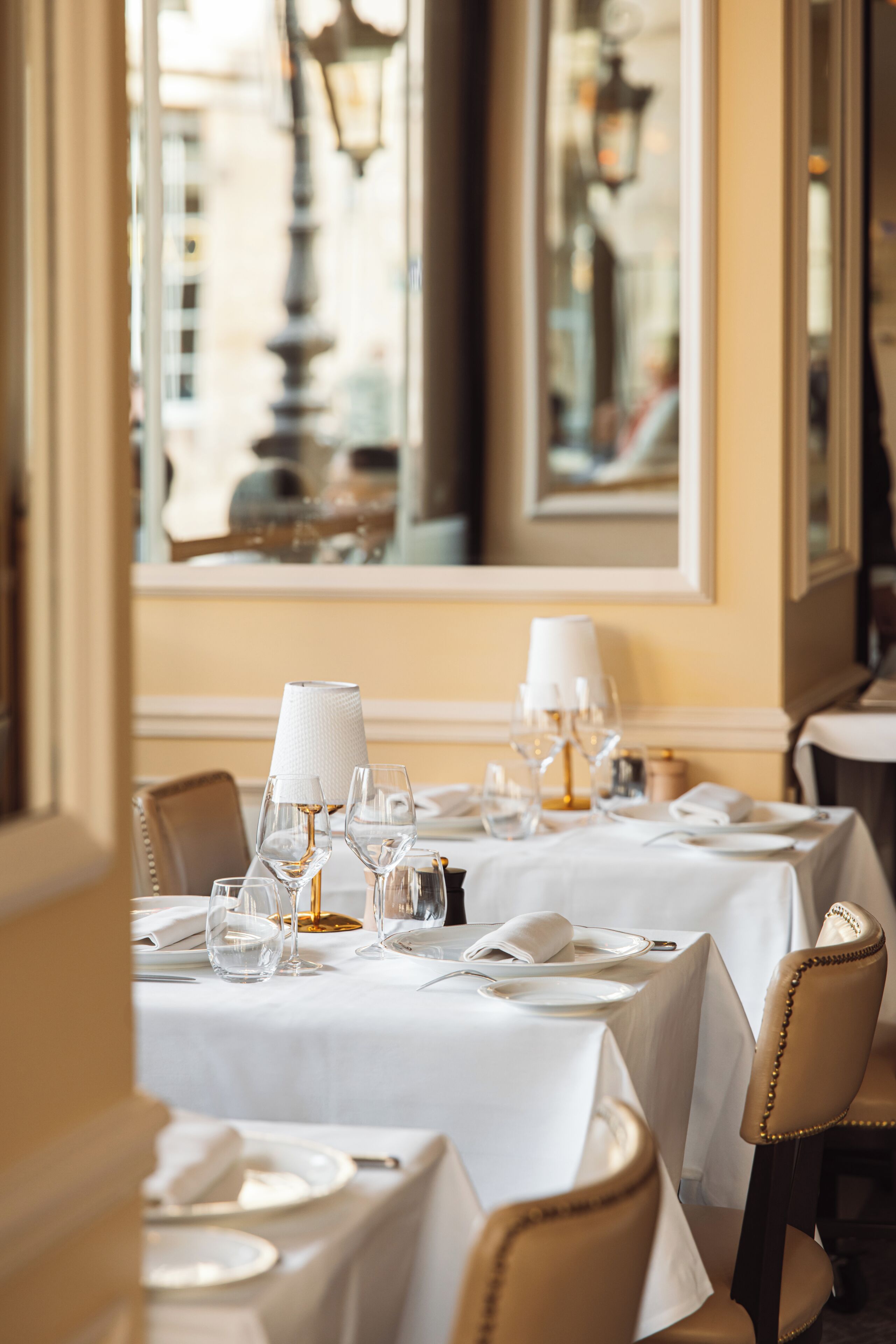 A restaurant interior with tables set for dining, featuring white tablecloths and glassware.