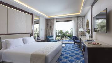 A hotel room with a large bed, a desk, a chair, and a view of a pool.