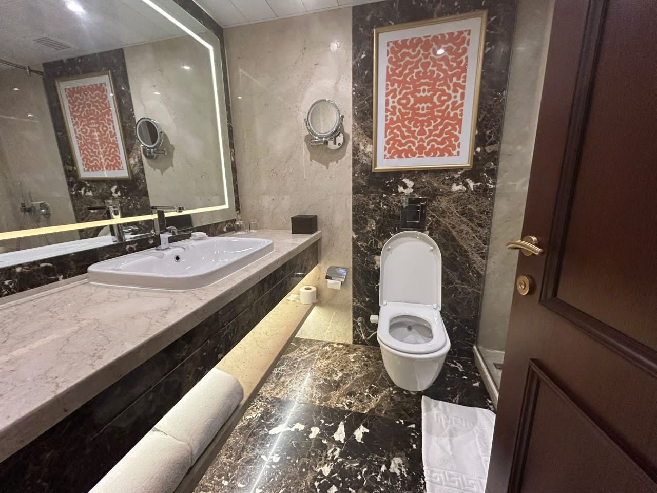 A bathroom with two sinks, a toilet, and a mirror.