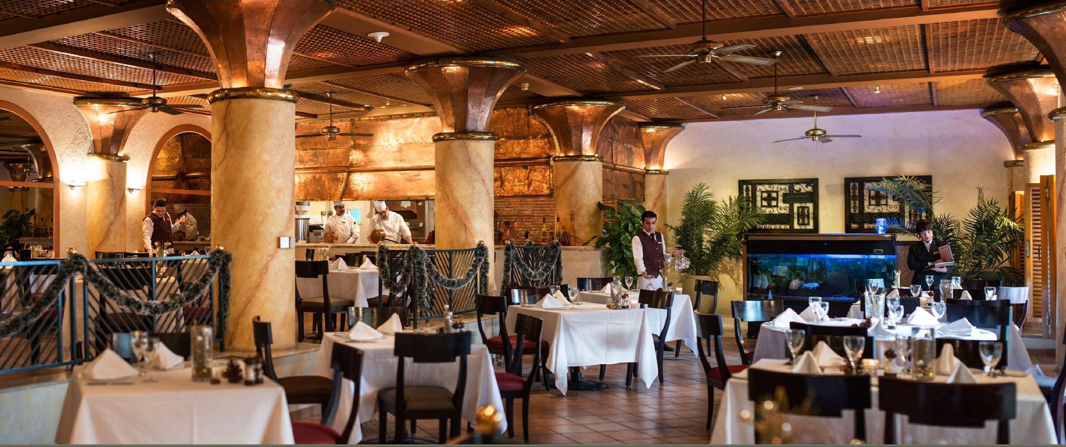 Ein Restaurant mit Marmorsäulen, mehreren gedeckten Tischen und Deckenventilatoren.