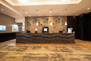 Welcome to our reception area, featuring a unique wavy-patterned desk and a digital display above, surrounded by decorative elements and a warm, inviting atmosphere.