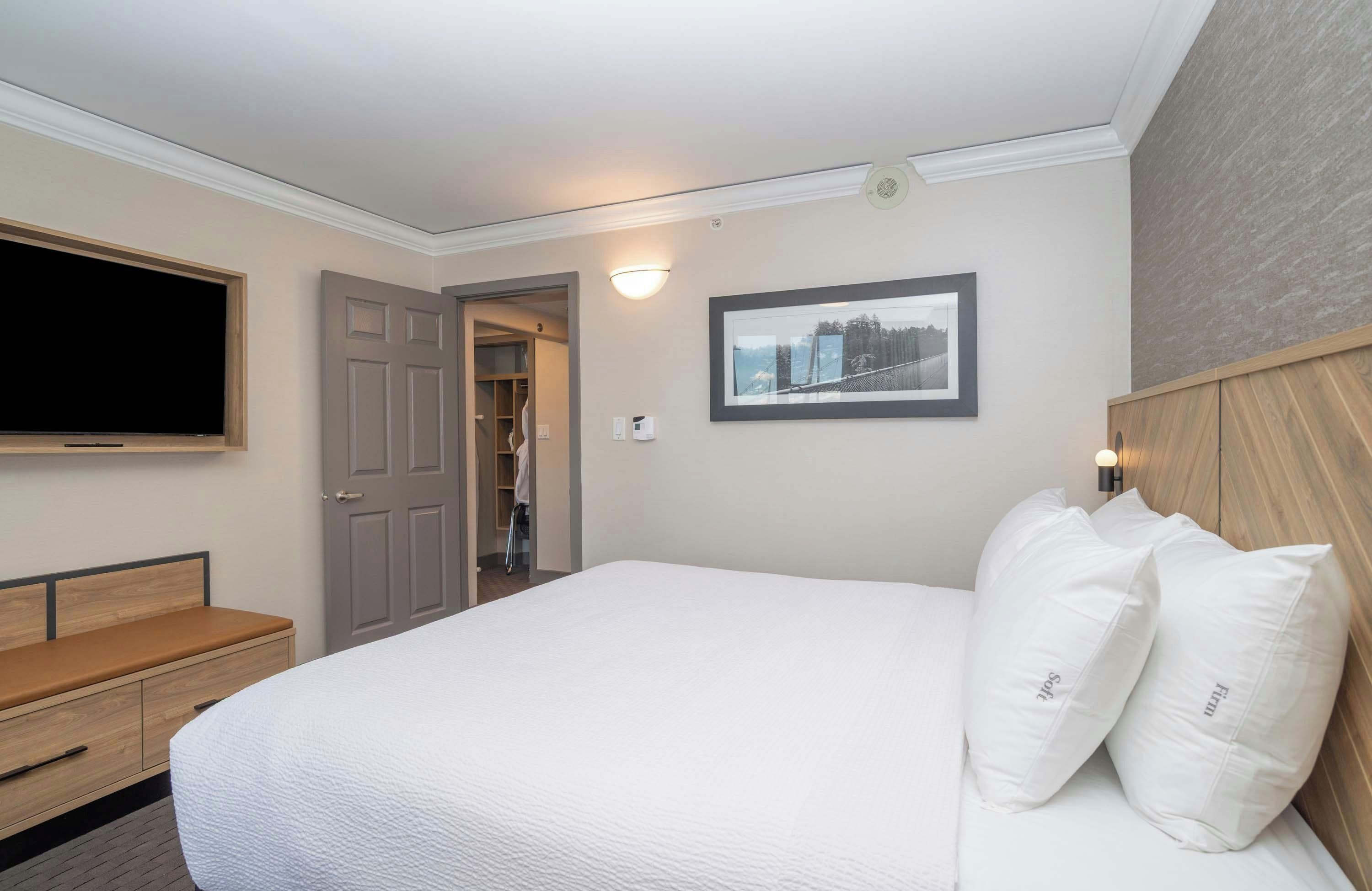 Une chambre d’hôtel avec un grand lit, une télévision, une armoire et un tableau encadré au mur.