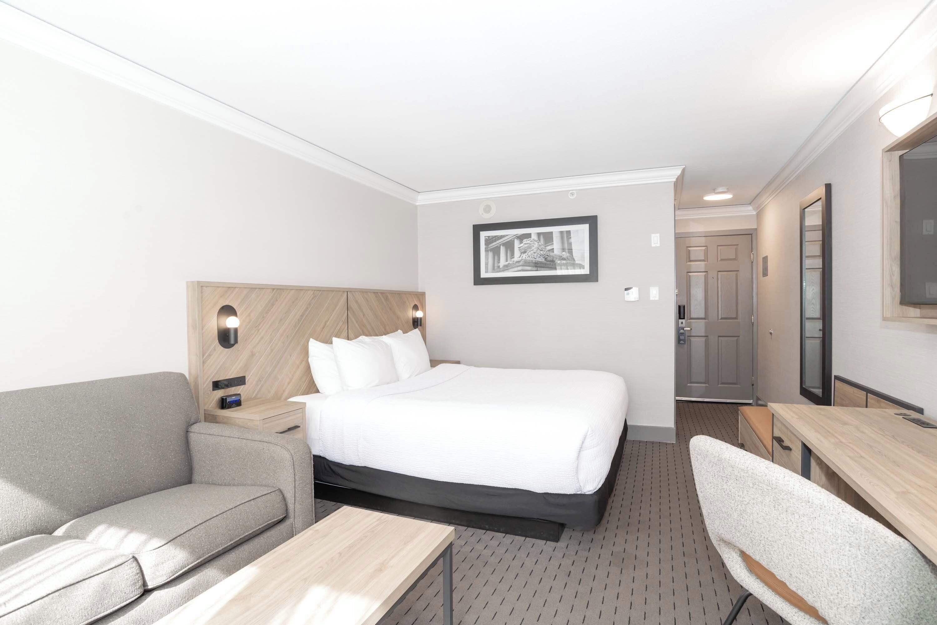 Una habitación de hotel con una cama, un sofá, un escritorio y un espejo.