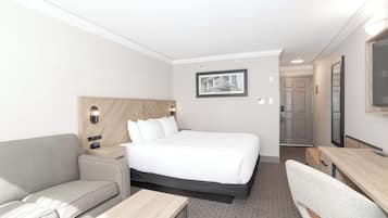 Una habitación de hotel con una cama, un sofá, un escritorio y un espejo.