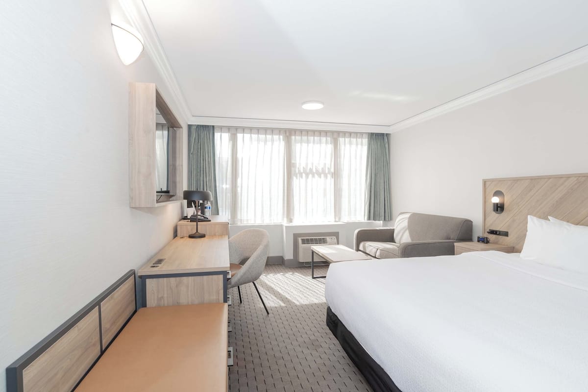 Een hotelkamer met een bed, bureau, stoel en een klein tafeltje.