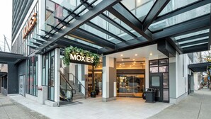 Un edificio moderno con fachada de vidrio y un letrero que dice "MOXIES".