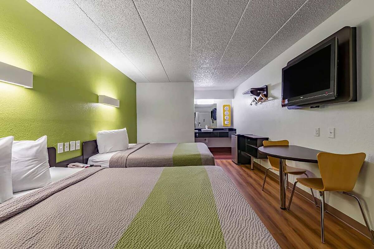 A hotel room with two beds, a TV, a desk, and a chair.