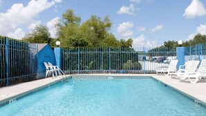 A clear blue swimming pool with white lounge chairs and a blue fence. - Days Inn by Wyndham Columbia NE Fort Jackson (Columbia)