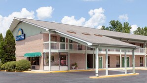 A Days Inn with a brick facade, a green awning, and a covered parking area. - Days Inn by Wyndham Columbia NE Fort Jackson (Columbia)