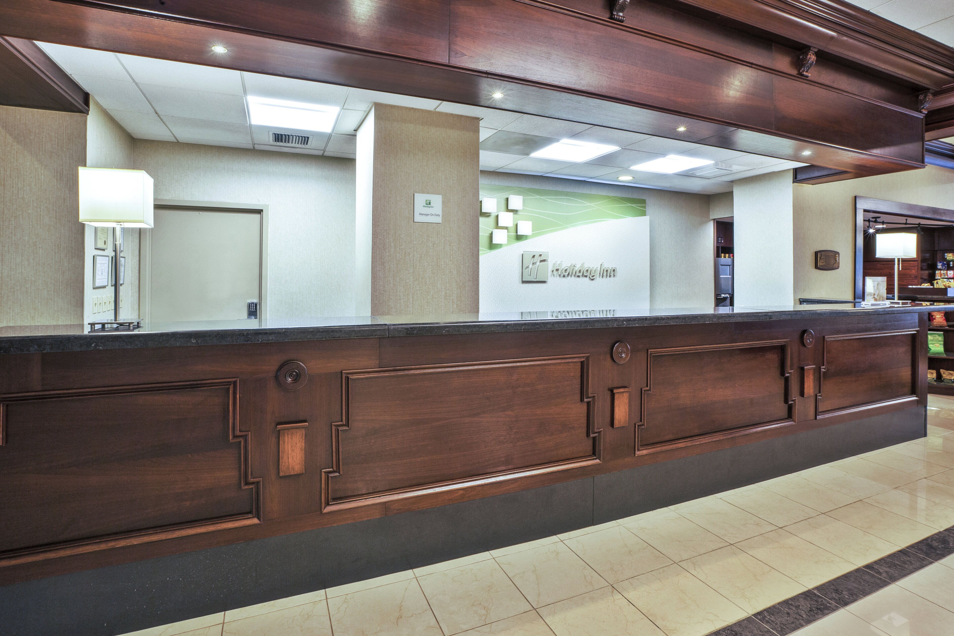 A reception desk with a 'Manager On Duty' sign, a 'Holiday Inn' logo, and a 'Manager On Duty' sign above the door.