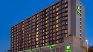 Un hotel Holiday Inn con fachada moderna, varios pisos y una entrada destacada con señalización iluminada.
