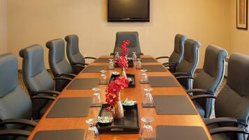 A conference room with a long table, black chairs, and a flat-screen TV on the wall.
