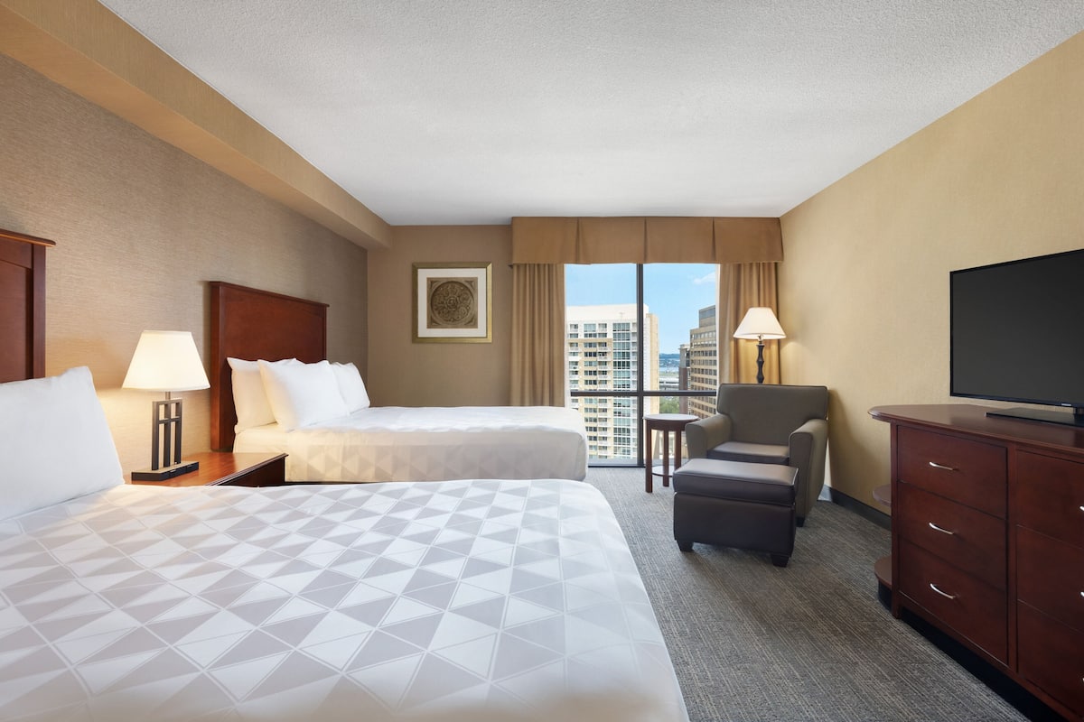 A hotel room with two beds, a TV, a desk, and a chair.